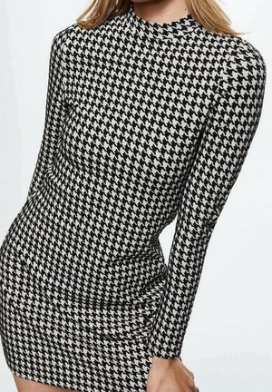 Robe à manches longues noire et blanche avec un motif pied-de-poule, dotée d'un col montant et d'une silhouette ajustée. Texture lisse, longueur courte.