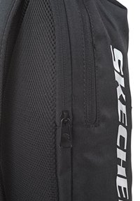 Mochila negra con un panel de malla, un cierre suave y el logotipo 'SKECHERS' en blanco. Tela duradera con un acabado texturizado y un diseño práctico.