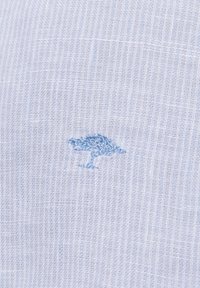 Hellblauem Stoff mit einer strukturierten Webart, die ein kleines, eingesticktes Design eines Baumes in einem etwas dunkleren Blauton zeigt.