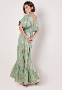 Robes maxi en vert menthe avec des motifs floraux dorés, design à dos en V, taille élastique et ourlet évasé. Tissu doux avec une silhouette fluide.