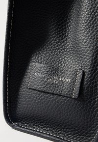Borsa tote in pelle nera con grana testurizzata, cuciture bianche sui bordi e un'etichetta impressa con "Gianni Chiarini Firenze."