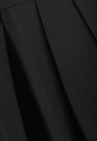 Tessuto nero con trama visibile, piegato per creare morbide pieghe sovrapposte e ombre.