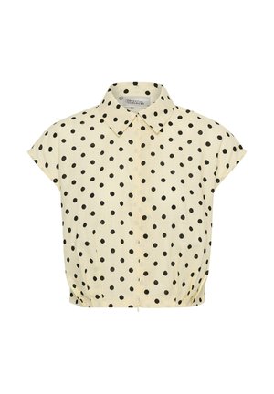 Bézs rövid ujjú blúz fekete pöttyökkel, hegyes nyakkal, elöl cipzárral és rugalmas szegéllyel.