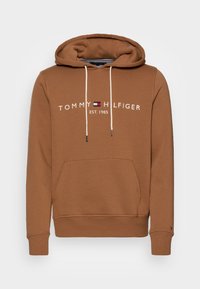 Sudadera marrón con un bolsillo tipo canguro, capucha con cordón y texto bordado en blanco "TOMMY HILFIGER EST. 1985." Tela suave y puños acanalados.