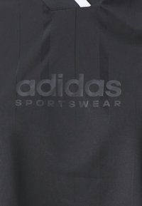 Černé sportovní tričko s embosovaným logem "adidas SPORTSWEAR", texturovanou látkou, jemnými vertikálními pruhy a minimalistickým designem.