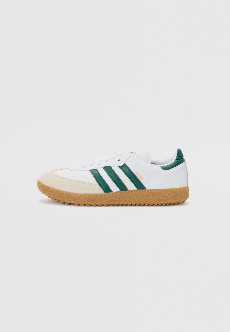 White sneakers with green stripes and yellow branding. Rubber sole with textured grip, suede toe cap, and mesh details on the collar.