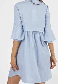Gestreiftes Kleid in Blau und Weiß mit lockerer Passform, schwingenden Ärmeln und gerafftem Taillenbereich. Hergestellt aus leichtem Stoff mit glatter Textur.