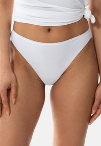 White bikini bottom with a low-rise cut, smooth texture, minimal coverage, and clean stitching details. Paired with a matching top.