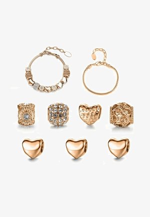 Goldfarbene Schmuckset mit einem Perlenarmband, Charms mit verschiedenen Texturen und herzförmigen Perlen mit Akzenten aus funkelnden Steinen.