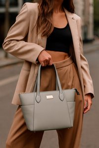 Grijze neplederen tote bag met dubbele handvatten, voorzien van een gouden embleemplaat, gestikte details en een gestructureerde rechthoekige vorm.