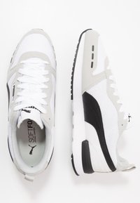 Valkoiset ja harmaat tennarit, joissa on verkkokangas päällinen, mustat yksityiskohdat ja valkoiset nauhat. Varustettu kumipohjalla, pehmustetulla sisäpohjalla ja logotiedoilla.