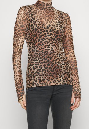 Přiléhavý top s dlouhým rukávem s hnědočerným leopardím vzorem, nošený s tmavě šedými džínami, osoba zobrazená od krku po boky.