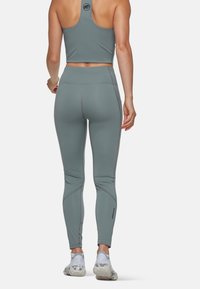 Haut de sport court et leggings en gris muted. Il présente un design ajusté avec des coutures contrastantes et un logo au dos du haut.