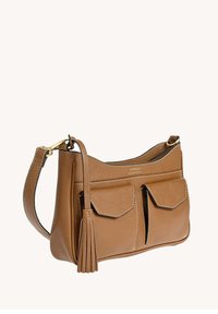 Sac à épaule en cuir marron avec deux poches à rabat à l'avant, boucle en or et gland décoratif sur fond beige.