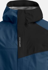 Blue and black waterproof jacket with a high collar, smooth texture, and a prominent logo on the side. Features a two-tone design.