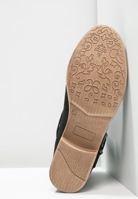 Czarne buty z teksturowaną gumową podeszwą. Podeszwa ma skomplikowany kwiatowy wzór. Rozmiar 37 oznaczony jest na spodzie.