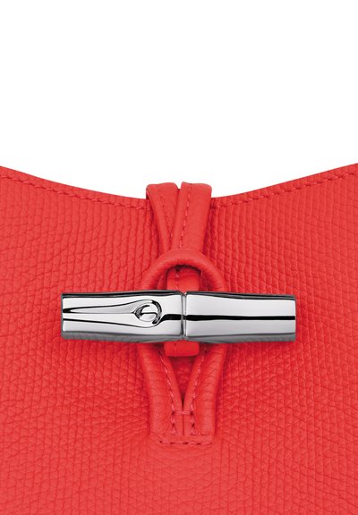 Red textured leather handbag with a sleek silver hardware closure and a knotted strap. The surface features a pebbled pattern.