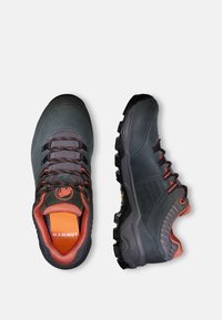 Scarpe da trekking grigio scuro con accenti arancioni, superficie testurizzata, lacci neri, suola con tasselli distintivi e linguetta imbottita e brandizzata.