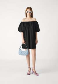 Svart off-the-shoulder kjole med pufferm, lyseblå håndveske med skrå hvite sømmer, og lilla stroppede høye hæler.