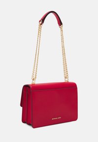 Czerwona skórzana torebka na ramię z złotym łańcuszkiem, prostokątny kształt, gładka tekstura, z złotym logo z przodu i kontrastującymi czarnymi wykończeniami.