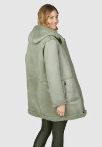 Groene fleecejas met een capuchon, een gestructureerde voering, een ritszak en decoratieve stiksels, met een losse pasvorm en een zachte afwerking.