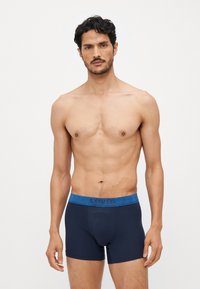 Námornícke boxerky s textúrovaným modrým pásom na ktorom je logo "LEVI'S". Elastický materiál, priliehavý strih bez viditeľných vzorov.