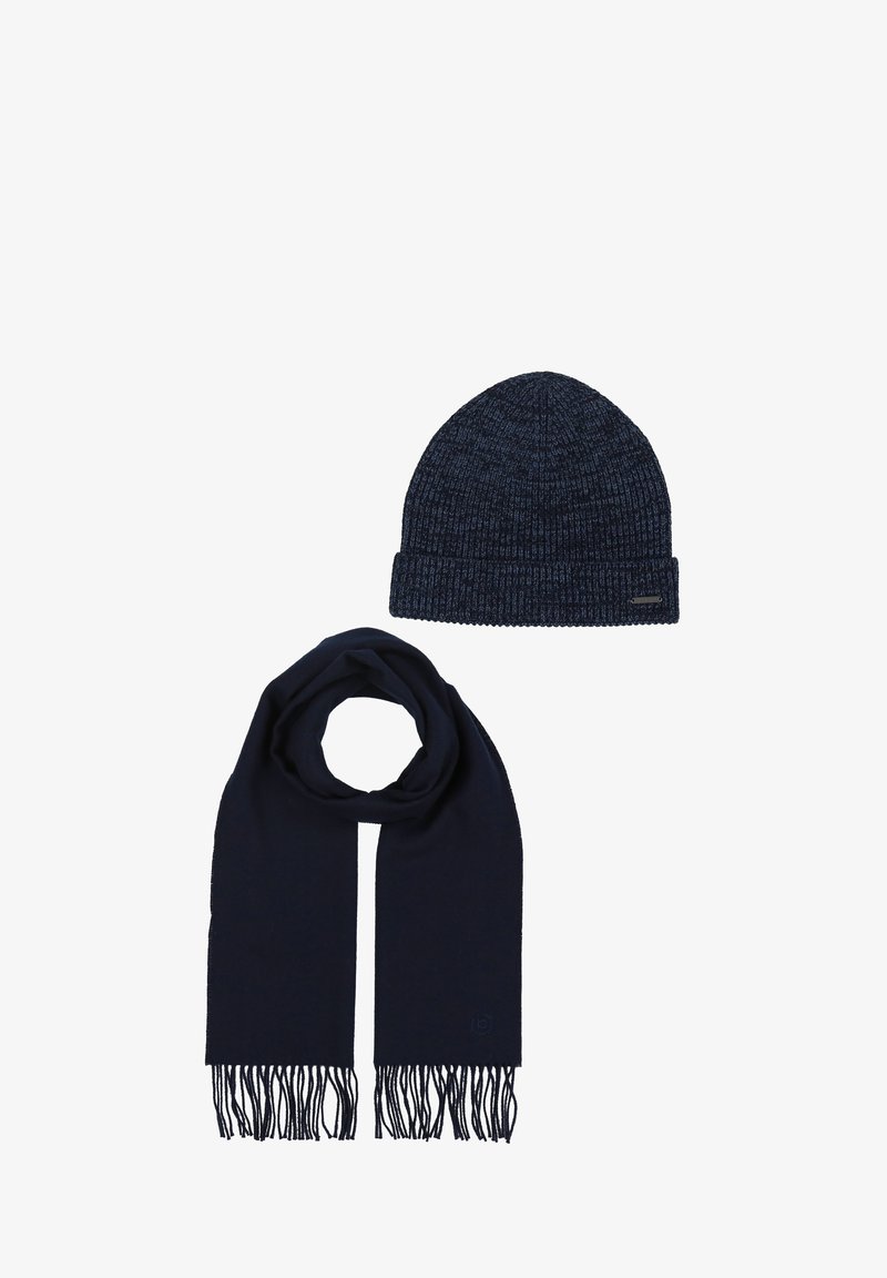Cappello a maglia color blu navy scuro con una texture a coste e risvolto piegato, abbinato a una sciarpa lunga coordinata con estremità frange.
