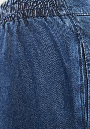 Pantalones de mezclilla con un tono azul oscuro, textura suave y una cinturilla elástica con detalles fruncidos para mayor comodidad.