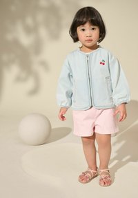 Hellblau gestreifte Jacke mit Kirschstickerei, rosa Shorts und beigen Sandalen mit floralem Akzent. Einfaches Design mit lockerer Passform.