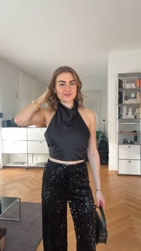 Haut noir à col licou associé à un pantalon noir à sequins. Le haut est lisse, tandis que le pantalon présente une texture brillante et réfléchissante.