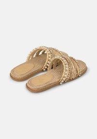 Open-toe slidesandalen met een tan geweven bovenkant, versierd met gouden kraaltjes en heldere edelstenen, met een platte jute zool en een textuur inlegzool.