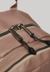 Zaino in tessuto rosa con doppie chiusure a zip, dettagli neri e superficie texturizzata con linguette nere.