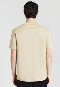 T-shirt beige a maniche corte con scollo rotondo, realizzato in tessuto liscio; presenta una vestibilità rilassata e orlo dritto, senza alcun motivo o dettaglio.