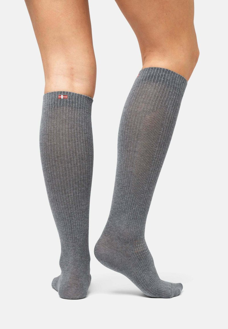 Grå knähöga strumpor gjorda av ett ribbat material. Har en enhetlig färg med en liten logotyp högst upp. Slät textur och åtsittande design.