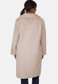 Cappotto lungo color beige chiaro, con una texture morbida, ampio colletto e vestibilità ampia. Senza chiusure visibili e con tasche laterali.