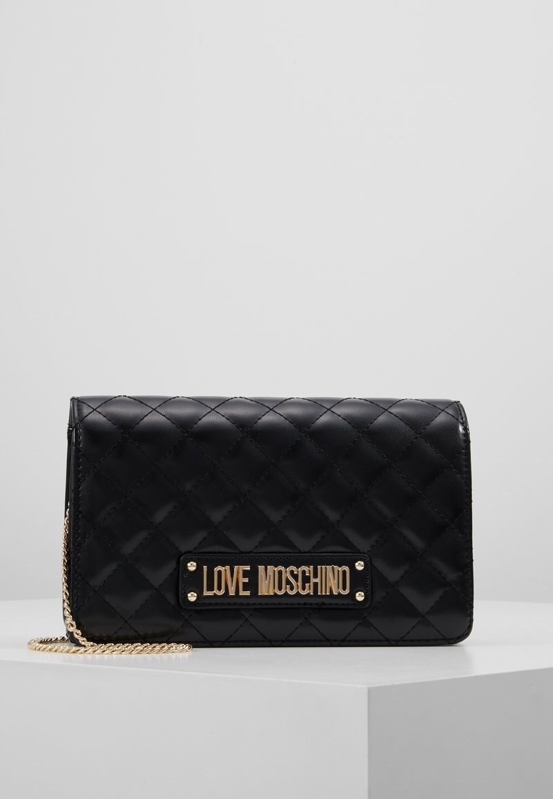 Musta tikattu käsilaukku, jossa on kultasävyinen laatta, johon on kaiverrettu "LOVE MOSCHINO", sekä ketjuhihna. Sileä pinta, jossa on neliökuvioinen yksityiskohtainen kuviointi.