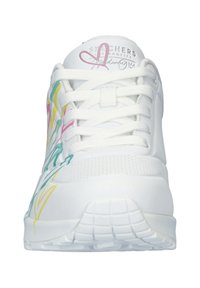 Chaussure de sport blanche avec une tige synthétique lisse, ornée de motifs floraux colorés en rose, jaune et vert. Fermeture à lacets et semelle texturée.