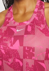 Top sportivo Nike di varie tonalità di rosa, caratterizzato da un motivo geometrico con dettagli testurizzati e un logo bianco sul petto.
