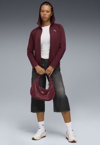 Burgundy hooded jacket with zip, white t-shirt, cropped dark jeans, and a glossy burgundy bag. White sneakers with dark sole and accents.