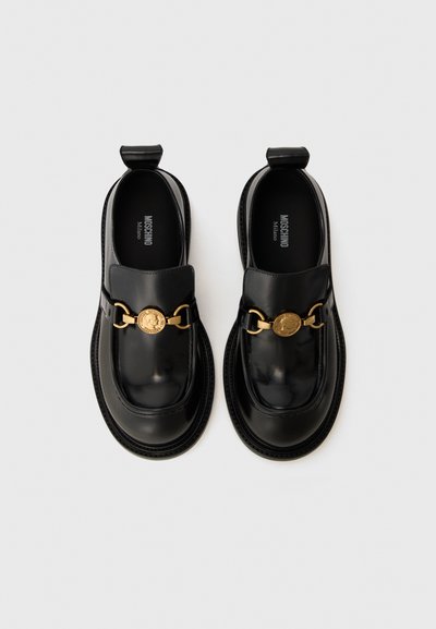Svarta läder loafers med en blank finish, som har ett guld kedjeaccent och en rund logodetalj på framsidan. Platt sula design.
