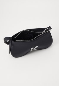 Borsa in pelle nera con una texture liscia, design curvo, hardware in argento e chiusura con zip. Presenta un logo impresso sulla parte anteriore.