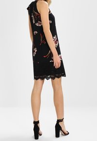 Musta ilmanhihaista mekkoa, jossa on kukkakuosisia, pitsireunat ja rento istuvuus. Yhdistetty mustiin paksupohjaisiin sandaaleihin.