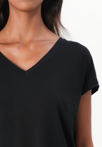 Black V-neck T-shirt made from smooth fabric, featuring short sleeves and a relaxed fit, with a subtle sheen and no visible patterns.
