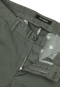 Grüne Baumwollhosen mit Knopfverschluss, Reißverschluss und gemusterter Innenauskleidung mit kleinen Herzdesigns. Inklusive Gürtelschlaufen.