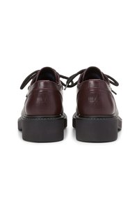 Burgunderfarbene Lederschuhe mit runden Zehen, schwarzen Gummisohlen, flachen Schnürsenkeln und dezentem Logodetail auf der Rückseite. Strukturierte Oberfläche und polierter Look.