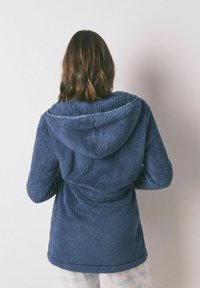 Marineblauwe fleece hoodie met een zachte textuur, voorzien van een capuchon en een voorkantzak, ontworpen voor comfort en warmte.