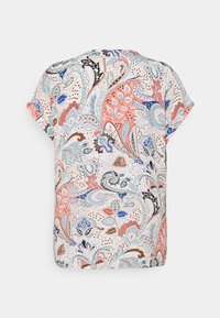 Blouse à manches courtes en tissu léger présentant un motif paisley multicolore avec des nuances de corail, de bleu et de noir sur un fond beige.
