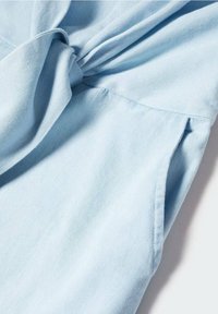 Vaaleansininen, pehmeä puuvillakangas, jossa on solmittu yksityiskohta sauman lähellä. Ominaisuuksina sileä tekstuuri ja valuva laskos, jotka soveltuvat arkivaatteeksi.