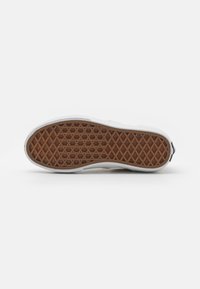 Suola di sneakers bianche con una finitura in gomma testurizzata. La suola presenta un motivo esagonale marrone per una migliore aderenza. Piccolo logo del marchio sul tallone.