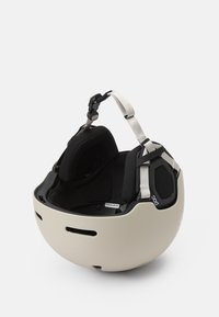 Skihelm in mattem Beige und Schwarz, mit Belüftungsschlitzen, verstellbaren Riemen und gepolstertem Innenraum für Komfort und Schutz.